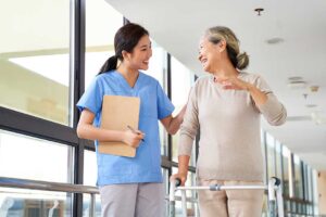 Older adult choosing clothing with a caregiver in a bright, private assisted living room