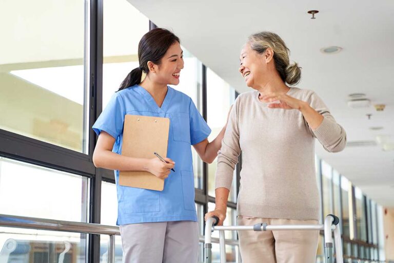 Older adult choosing clothing with a caregiver in a bright, private assisted living room